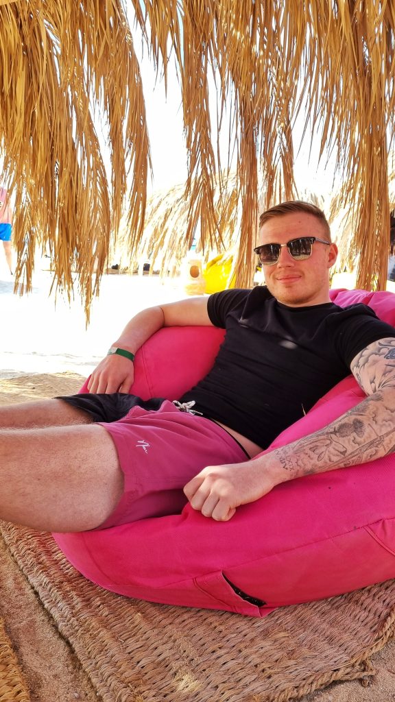 Liam sitting on a bright pink bean bag on Paradise Island.