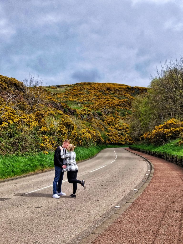 Road leading up to Holyrood Park with Amy and Liam kissing in the middle