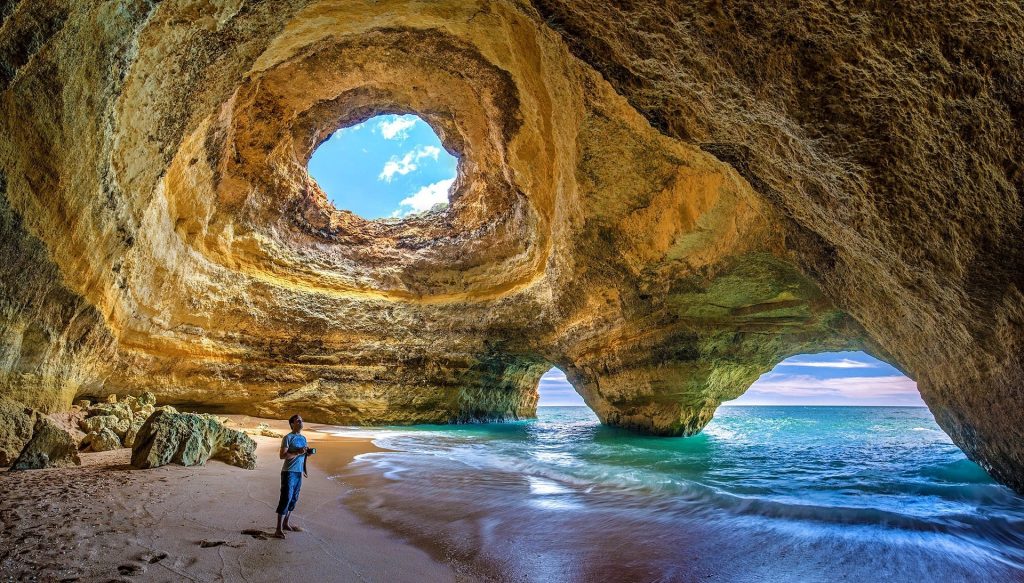 One of the best things to do in Faro, Portugal is to visit the Benagil Caves. This image shows the beauty of the caves with the sun shining through one of the holes in the cave.