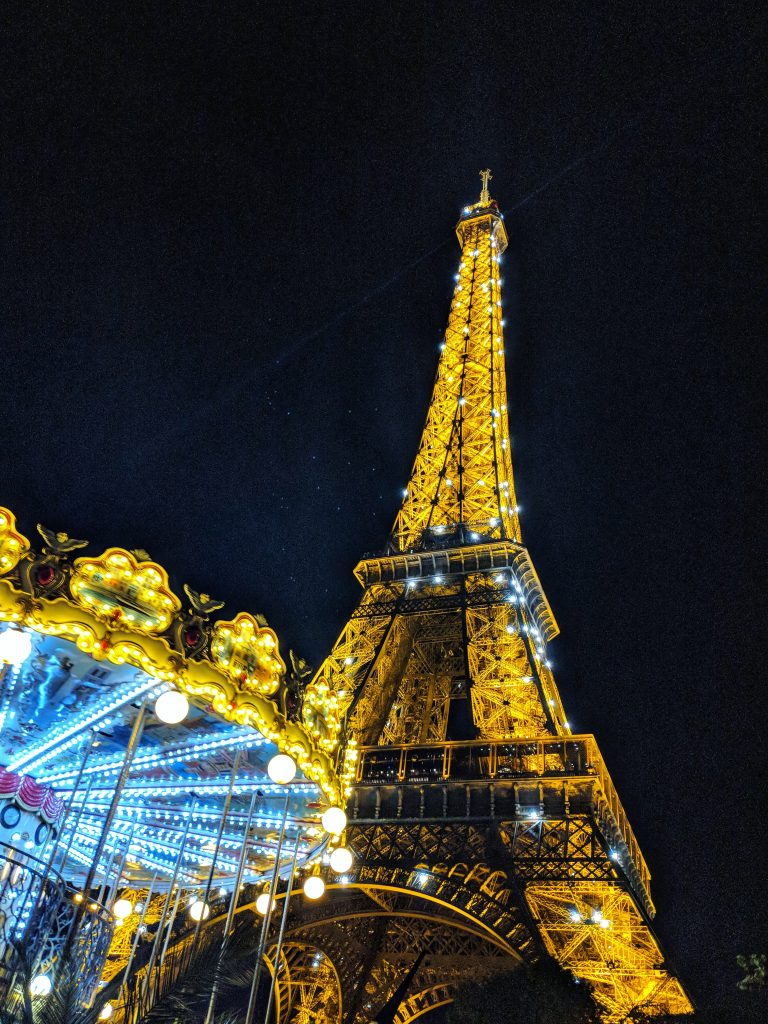 The Eiffel tower and a ferris wheel lit up at night