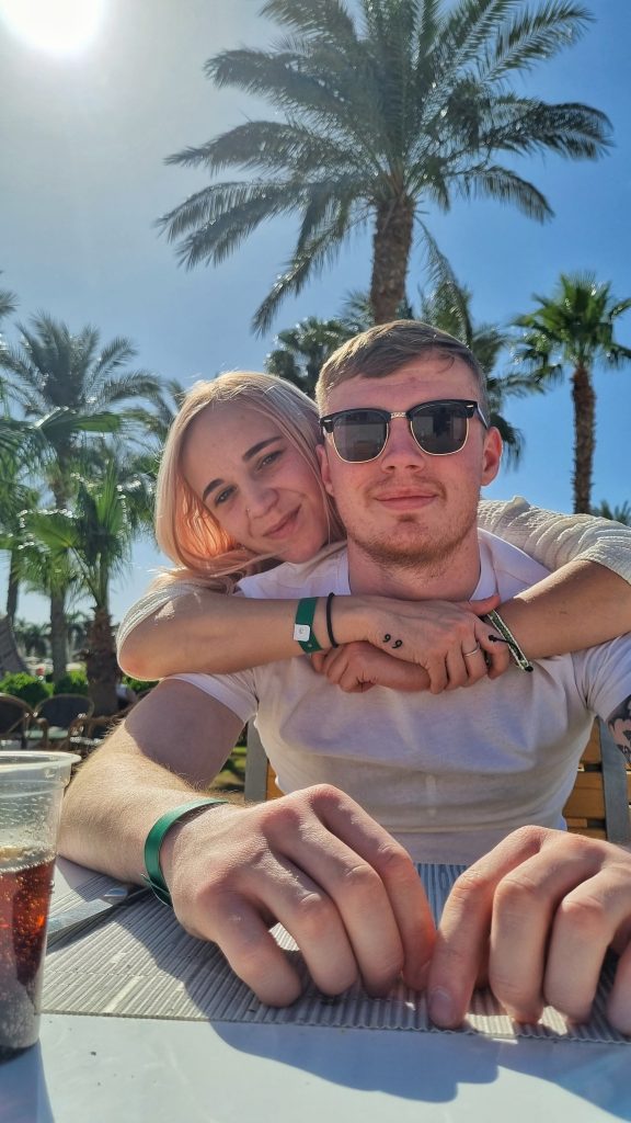 Amy and Liam enjoying their time In Hurghada with palm trees in the background.