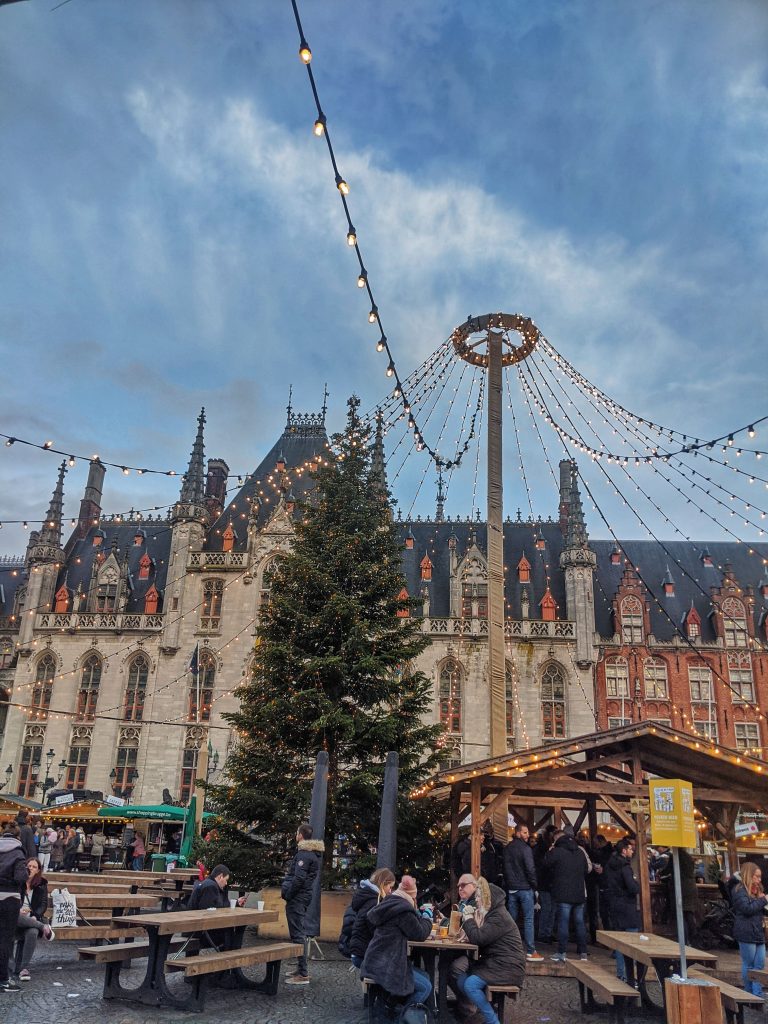 Tourists enjoying some of the food that they purchased at the Christmas Markets with the Christmas tree in the background.
