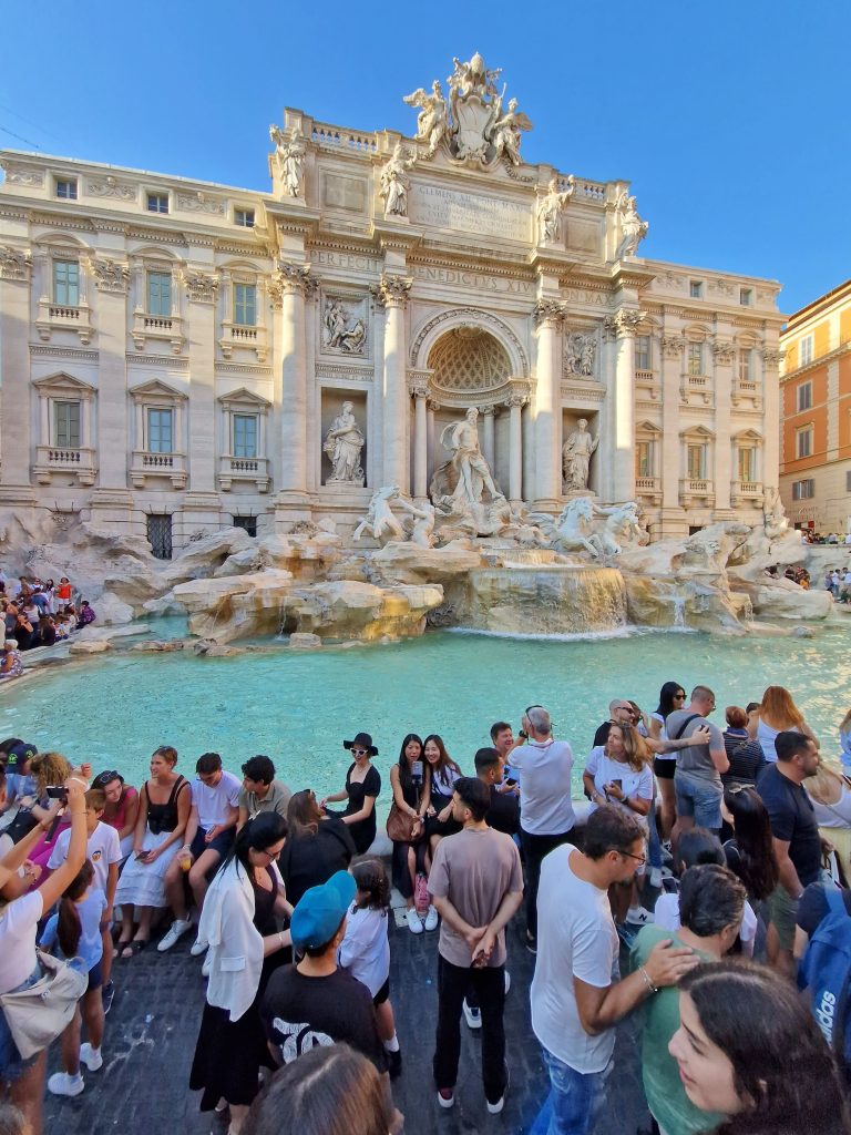 Crowd of people around the Trevi Fountain in Rome.