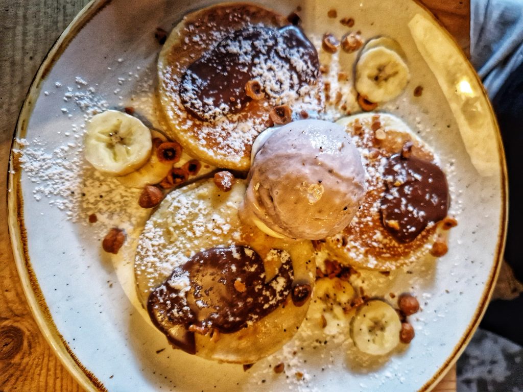 Super yummy pancakes with chocolate sauce, nuts, banana, chocolate ice cream and nuts.
