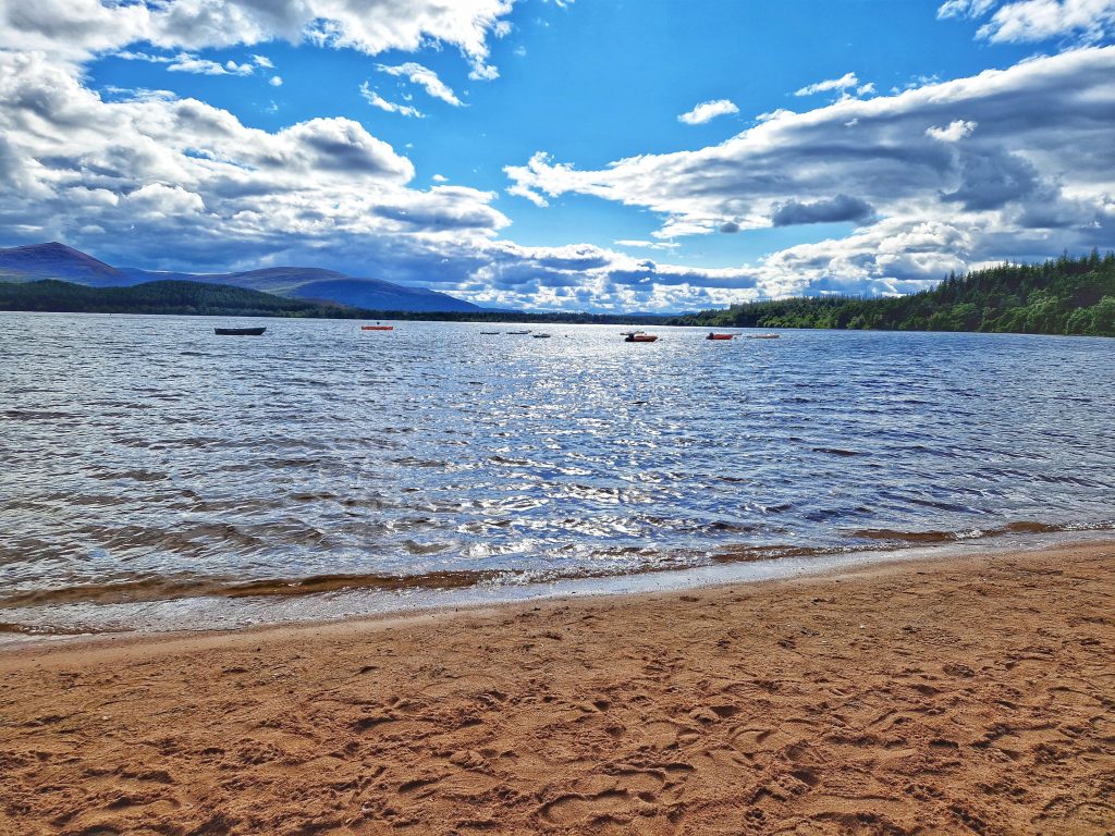 Beautiful view of Loch Morlich with kayaks and boats in the distance.