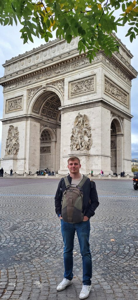 Liam posing in front of the Arc de Triomf with his rucksack on the front of his body.