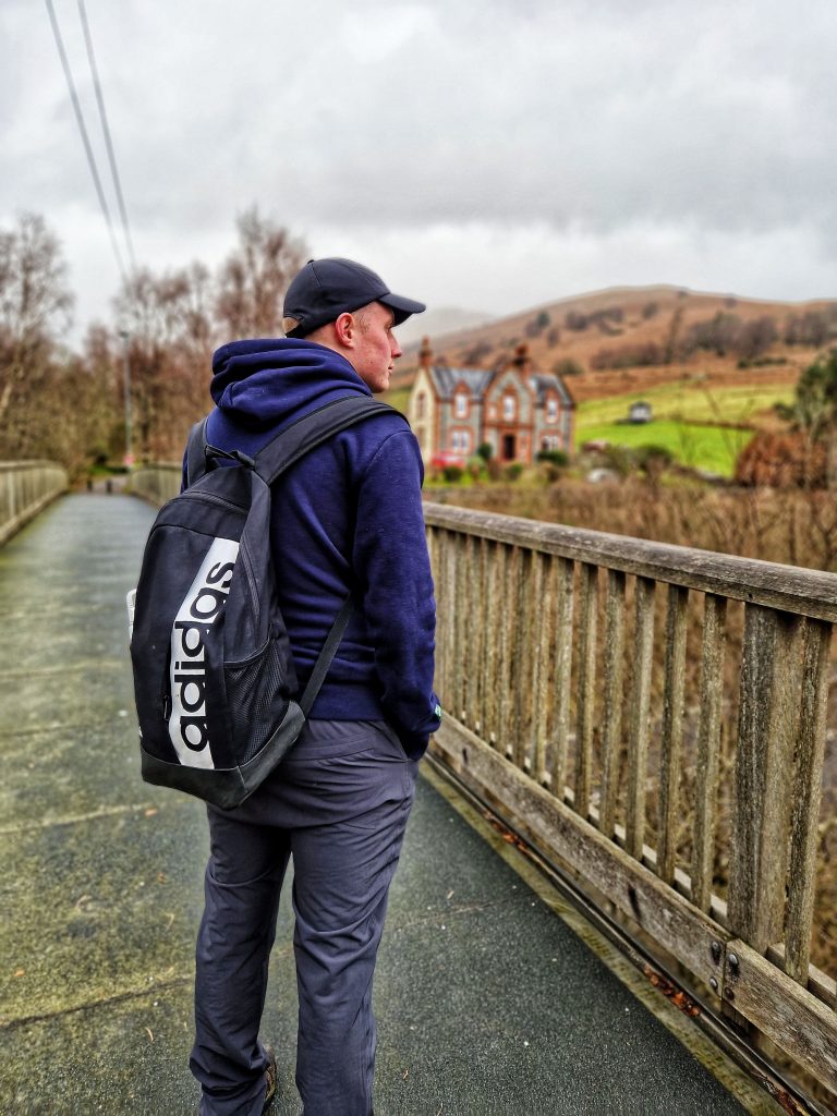 Liam looking into the distance enjoying the view with a beautiful house and some hills in the background.