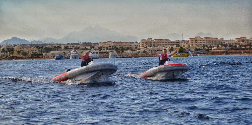 Amy & Liam enjoying a speedboat experience in Hurghada. Behind them you can see the city of Hurghada and the mountains in the distance.