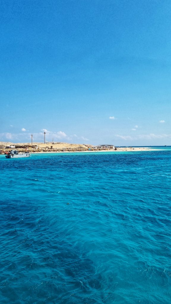 The stunning view of the Red Sea with a boat and paradise island in the background.