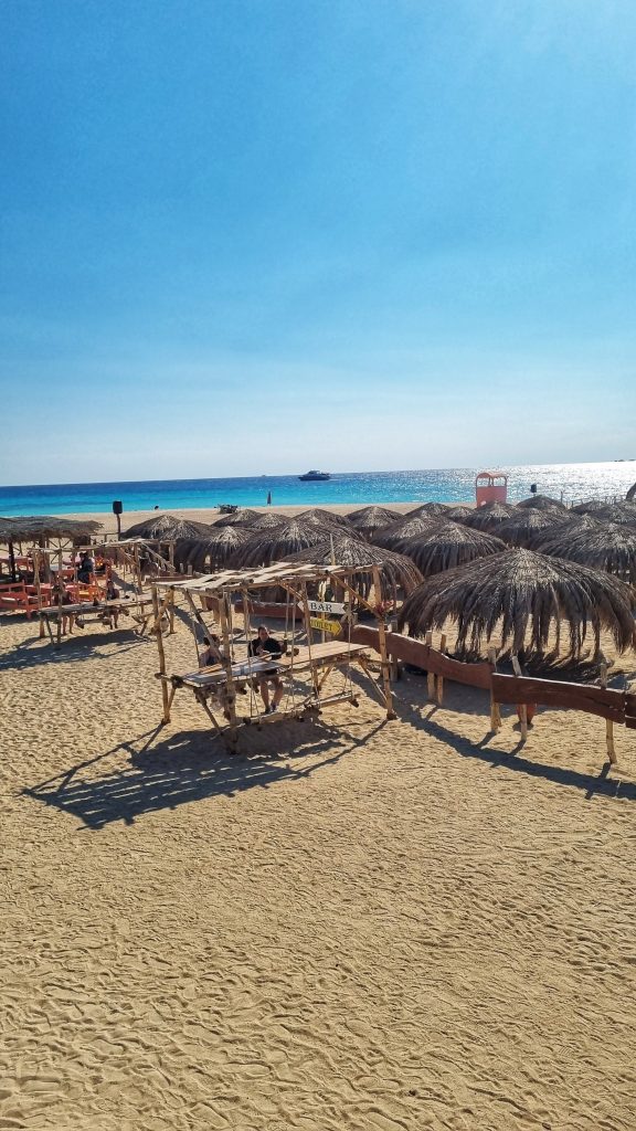 If you've come to this article then you will be asking yourself; Is Paradise Island from Hurghada worth it? Yes it absolutely is! This image shows the beautiful palm tree parasols, bright blue water and golden sandy beach.