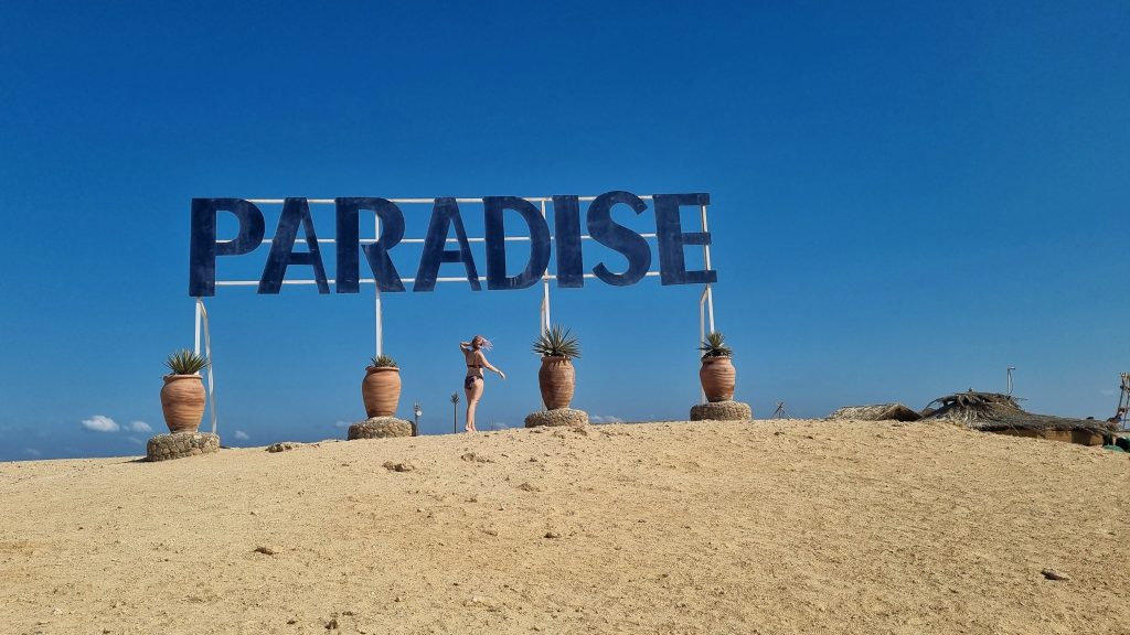 Paradise Island sign with Amy looking up at it.