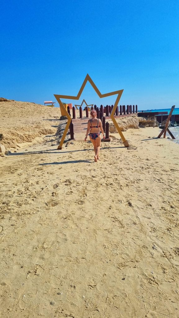 Amy walking on the sand on Paradise Island about to cross the bridge with stars around it.