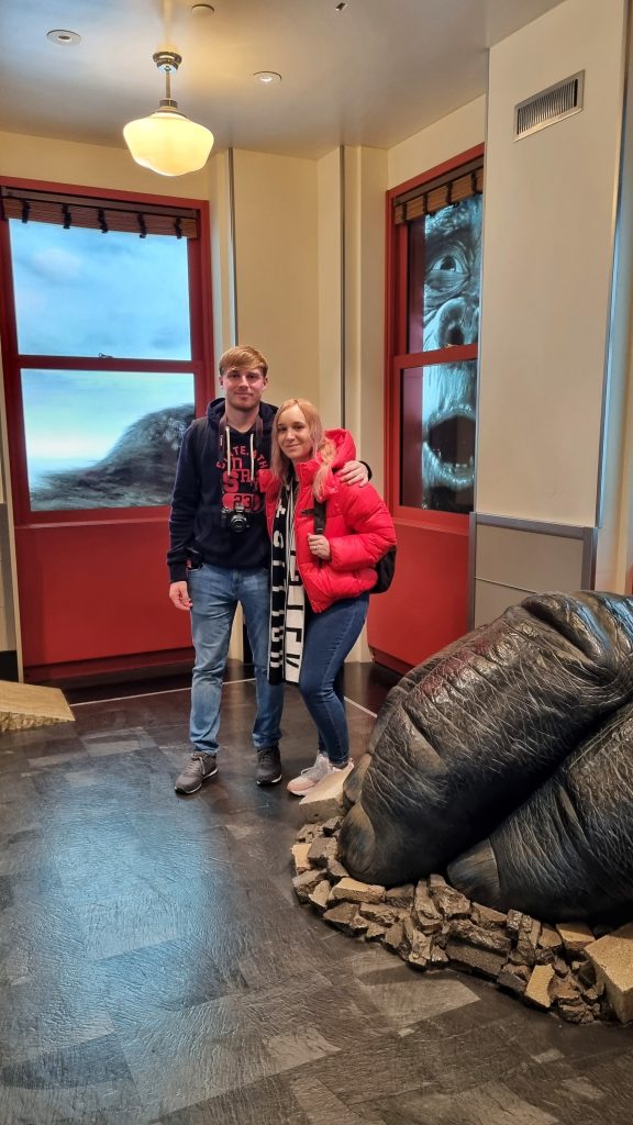Amy and Liam in the Empire State Building taking a photo with an animated King Kong behind them.