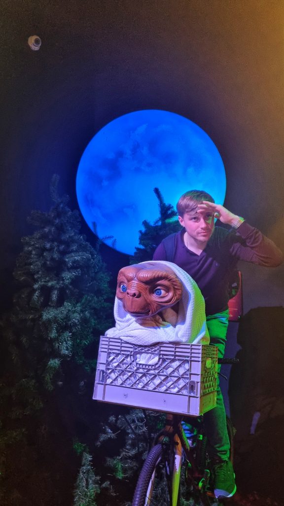 Liam enjoying Madame Tussauds by sitting on a bike with a wax figurine of ET in the basket.