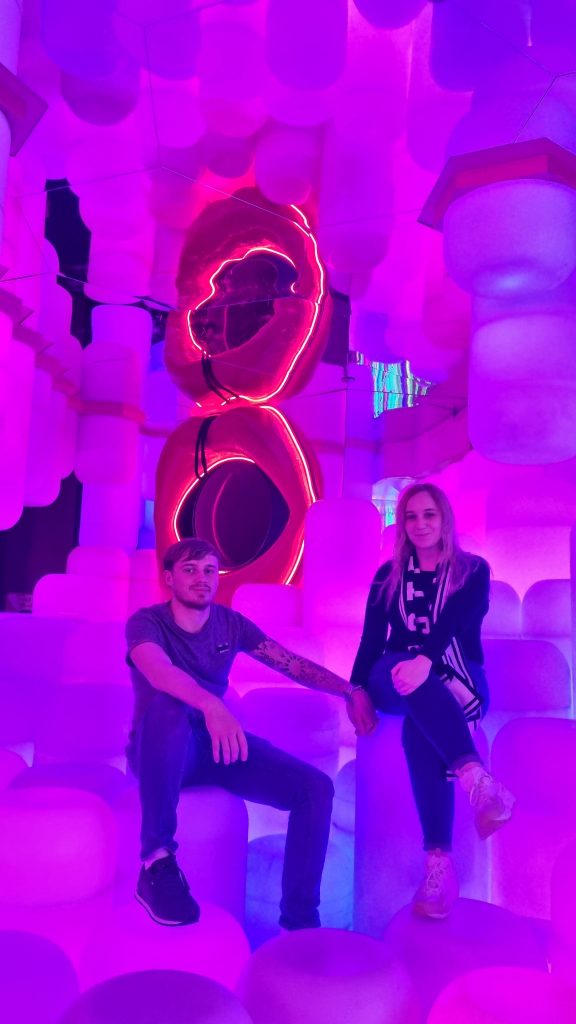 Amy and Liam sitting at the Museum of Sex close to one of the slides that is part of the funland.