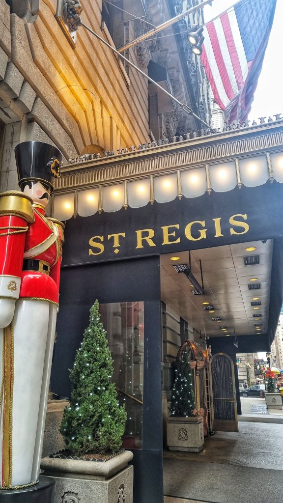 If you're visiting New York then one of the most romantic things to do in NYC. This image shows the St. Regis hotel with an American flag flying above and also a nutcracker standing next to the hotel.