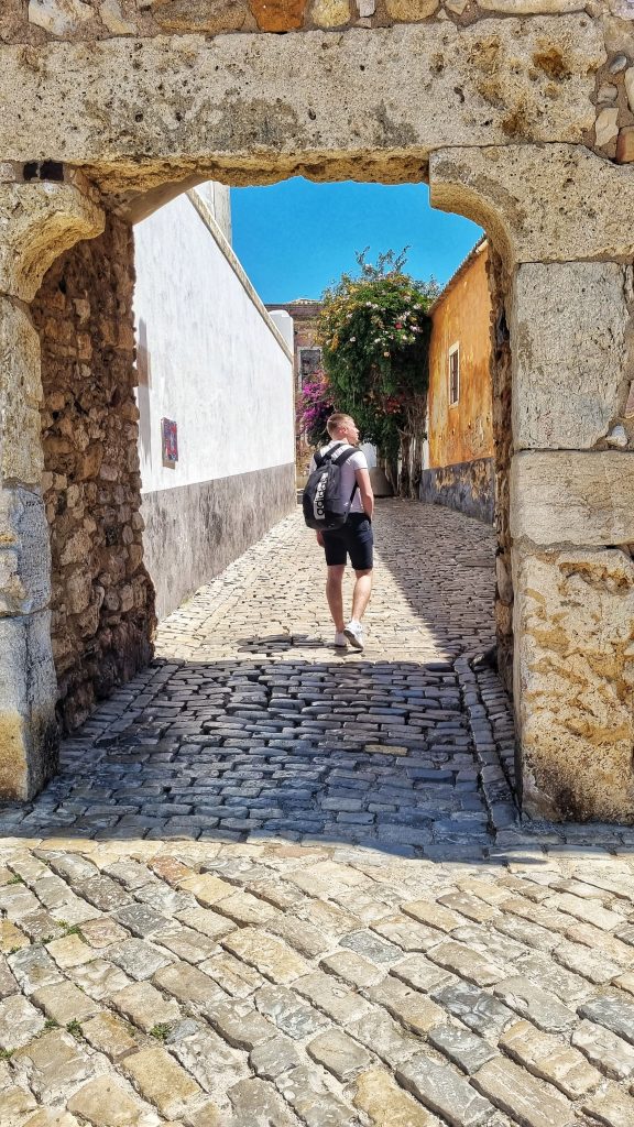 Liam walking through one of the arches in Faro's Old town admiring the beauty of the old city.