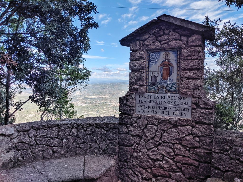 One of the religious plaques on Montserrat with viewpoint of the hills in the background.