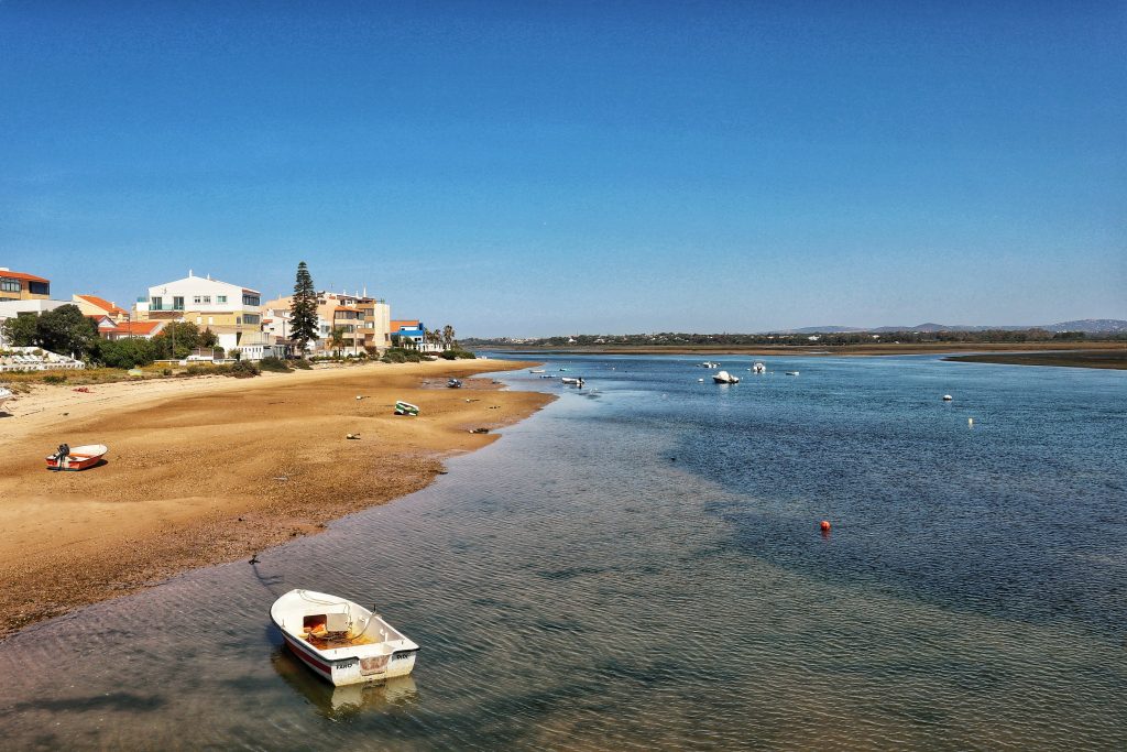 One of the most beautiful beaches in Faro where you can see the lagoon and the fishing boats across the beach and in the shallows of the water.