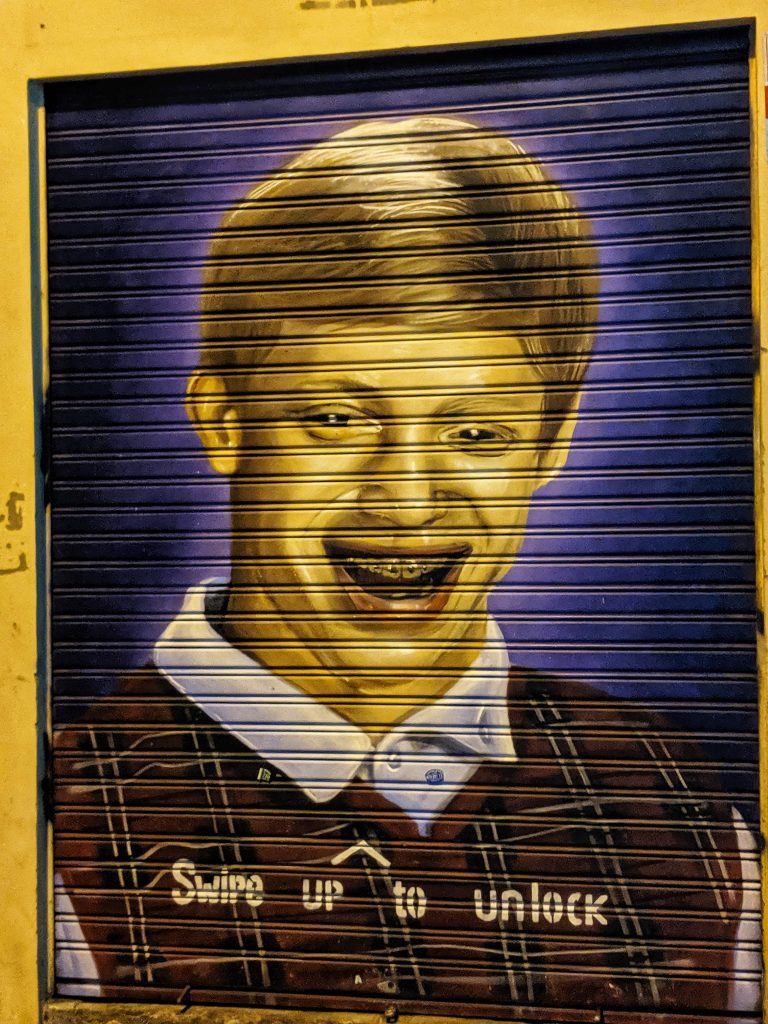 Some of the street art in Barcelona. This particular image shows a guy that once was a popular meme with the writing 'swipe up to unlock'