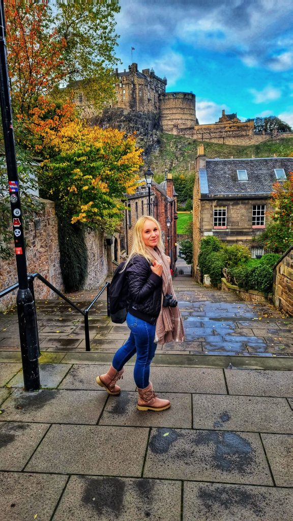 Amy standing at the top of the vennel steps with a view of Edinburgh Castle in the background.