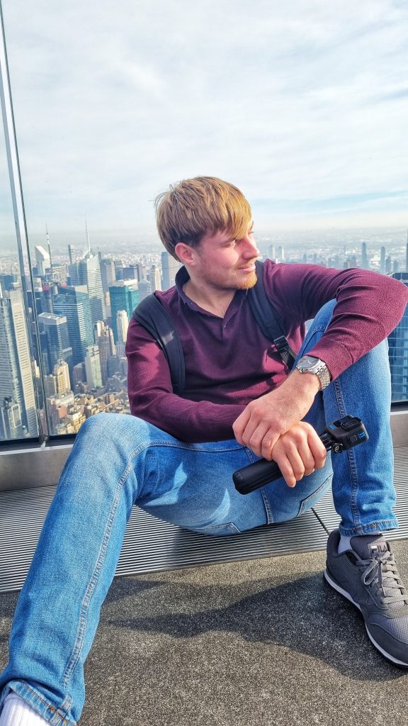 Liam sitting at the Edge observation deck with the city skyline in the background.