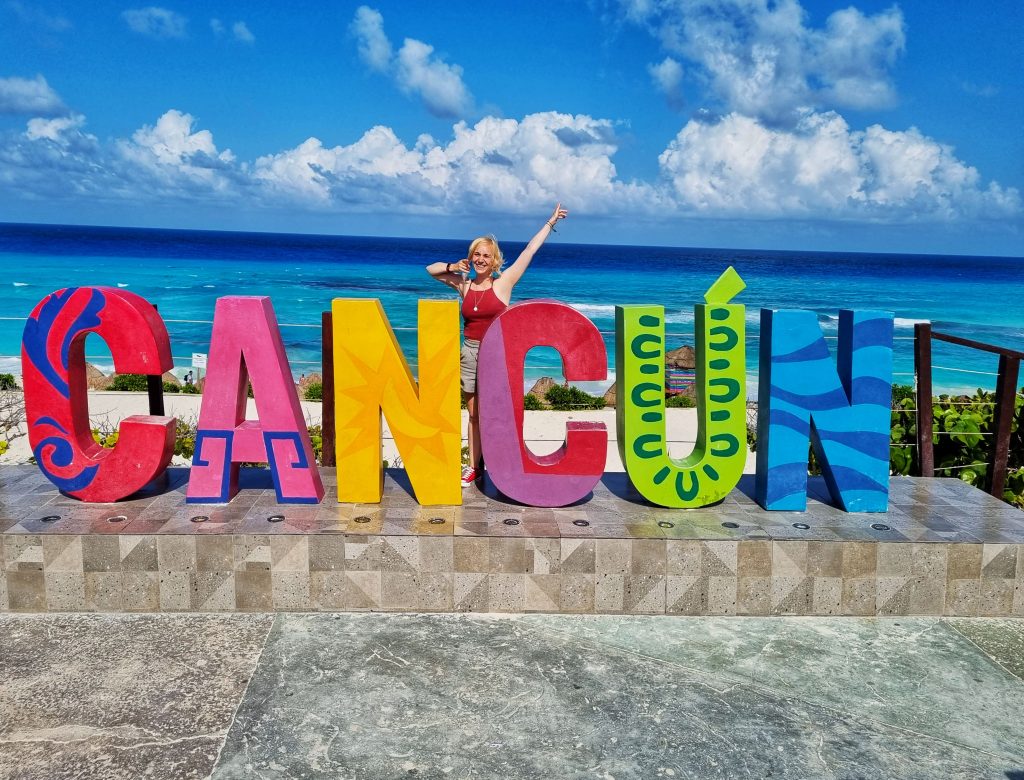 Amy standing with the Cancun sign