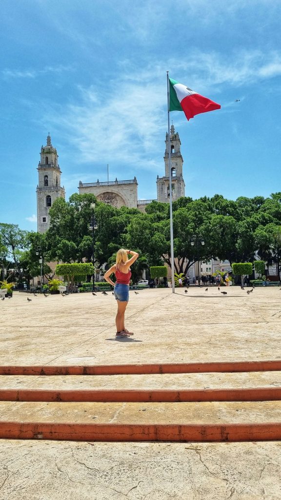 Amy exploring Merida and looking up at the Mexican flag in the zocalo