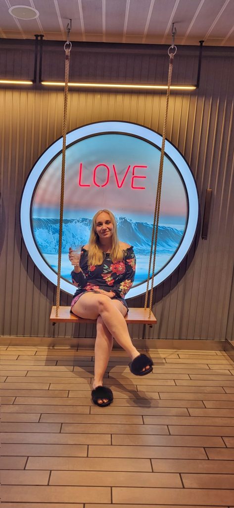 Amy sitting on the swing in front of the love sign.