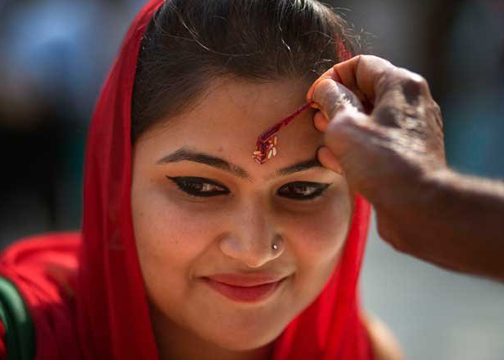 Pandit apply kumkuma on the woman's forehead in temples