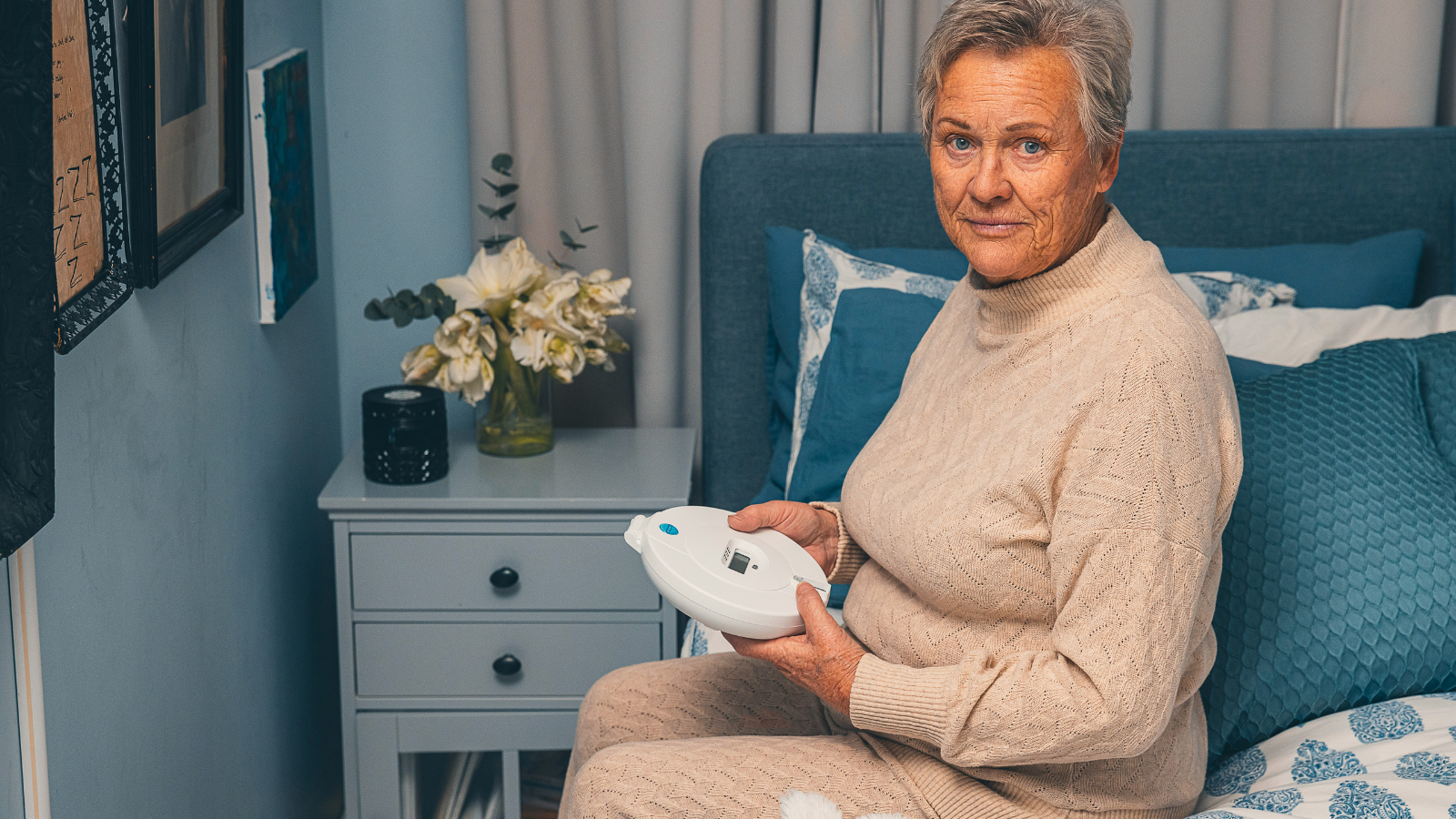 A woman sits on the bed with a medicine reminder.