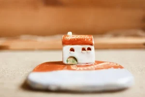 Mały ceramiczny domek na drewnianej powierzchni.