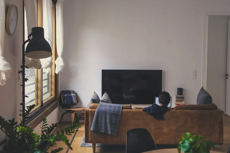 Przytulny salon z telewizorem, sofą i dużymi oknami.