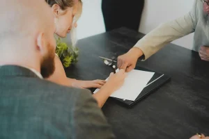 Kobieta podpisująca dokument u urzędnika.
