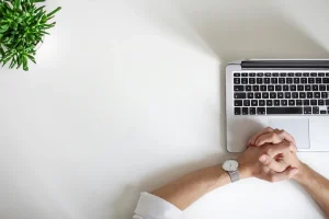 Ręce mężczyzny znajdujące się na stole przed komputerem.
