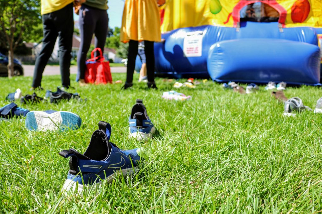 Picture of some shoes on the grass in front of a bouncy castle