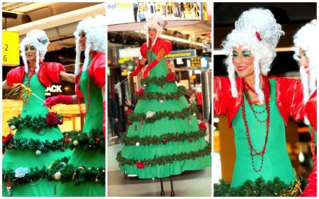 Betoverend kerstentertainment: Kerstboom Lady's Steltenlopers brengen magie met guirlandes en lampjes. Boek nu voor feestelijke sfeer!