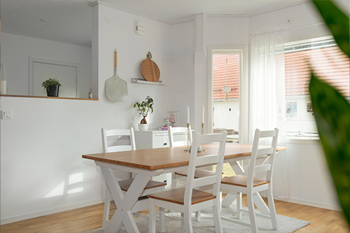 En vit matsal med ett Prime Foto ovanför träbordet och stolarna.