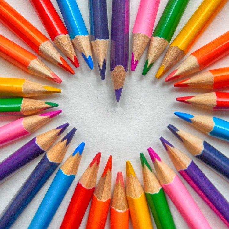 rainbow coloured pencils arranged in heart shape