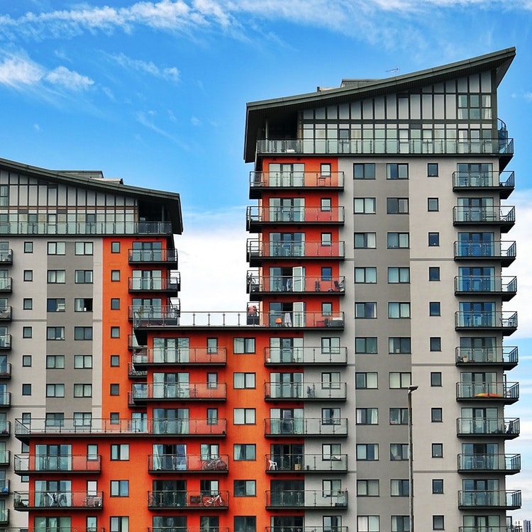 orange and grey apartment block with blue sky and white clouds