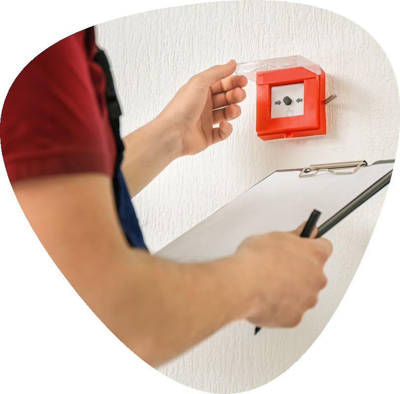 fire alarm being inspected by person holding clipboard and pen