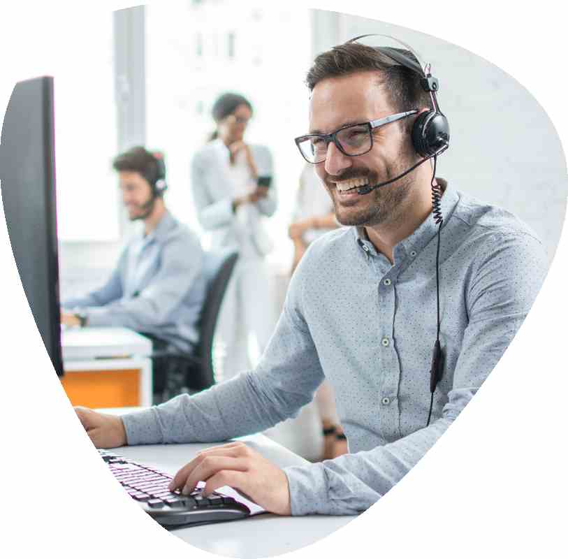 man sat at office desk wearing phone headset smiling