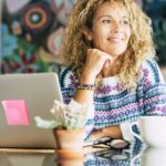 Portrait of beautiful blonde caucasian woman smile and work with laptop computer at home