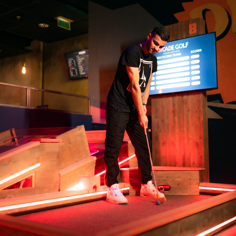 Joueurs jouant à l'arcade golf dans une ambiance animée.