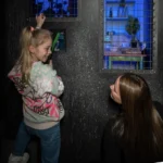 Une petite fille et sa maman en pleine activité lors d’une sortie en famille à Bruxelles avec enfants, explorant un jeu interactif à Prison Island.