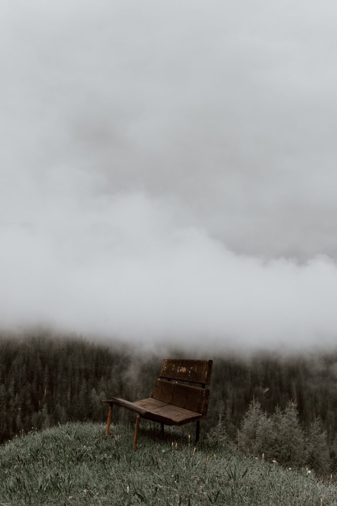 een foto van een bankje alleen op een heuvel met mist. Het weergeeft de eenzaamheid die je kunt voelen bij PTSS na verkrachting of aanranding