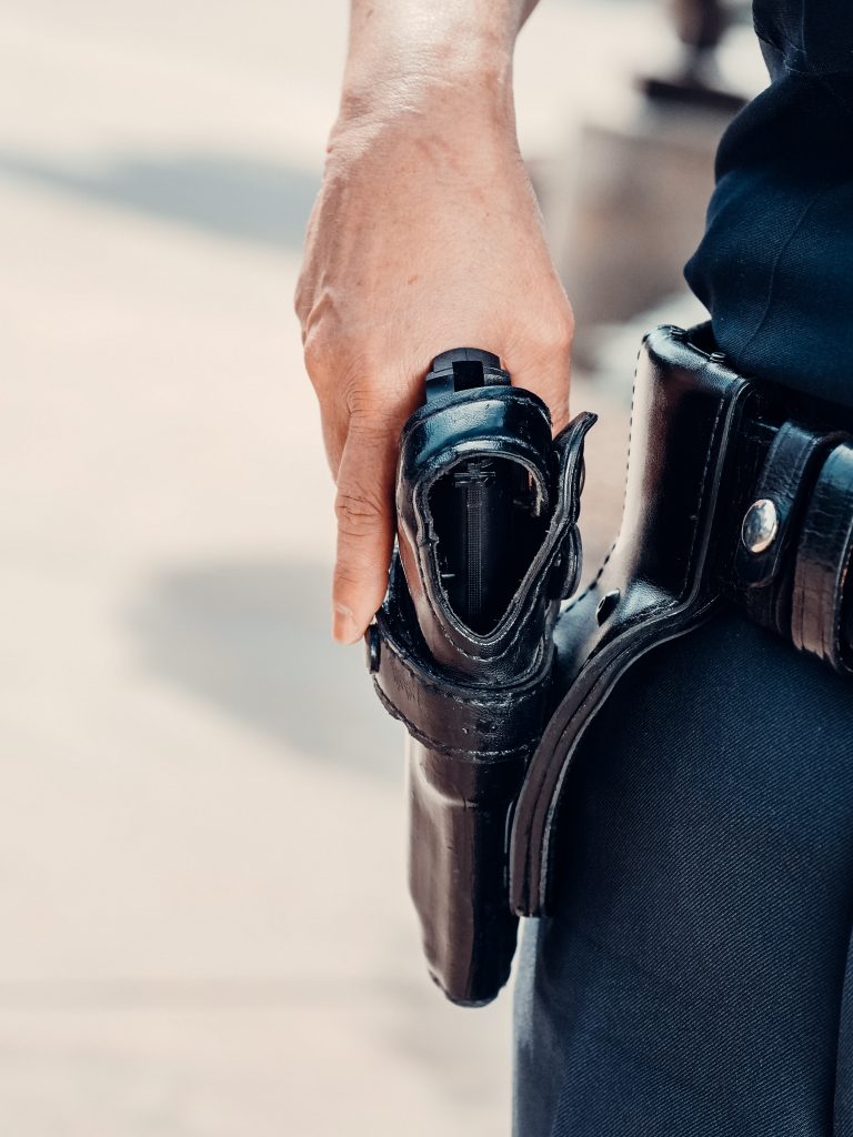 Op deze foto zie je een agent die naar zijn pistool grijpt. Het weergeeft mogelijk trauma bij uniformberoepen door heftige incidenten