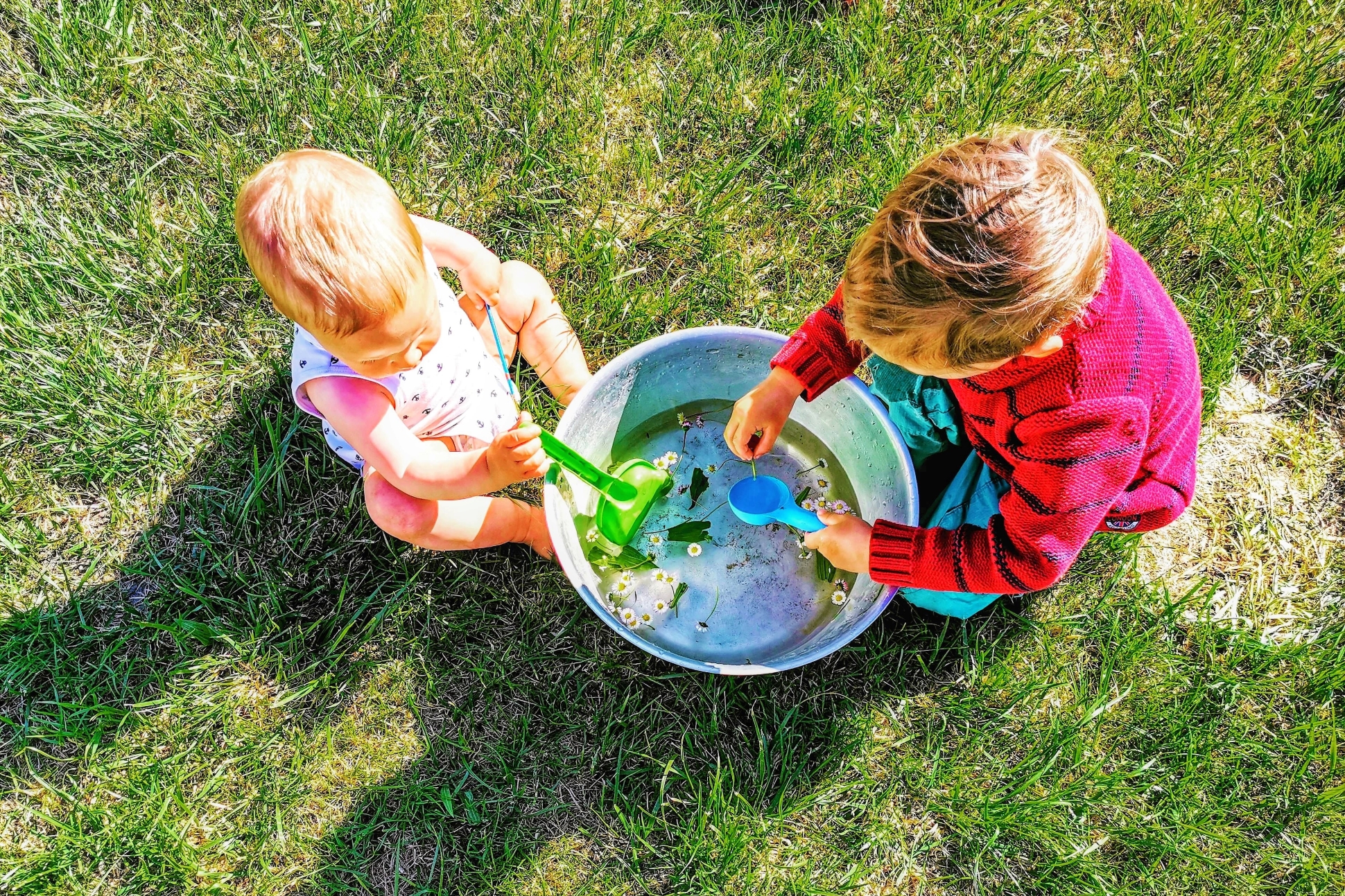Kinder spielen im Garten gern mit Naturmaterialien. Eine Schüssel und verschiedene Gräser und Pflanzen sind oft genug.