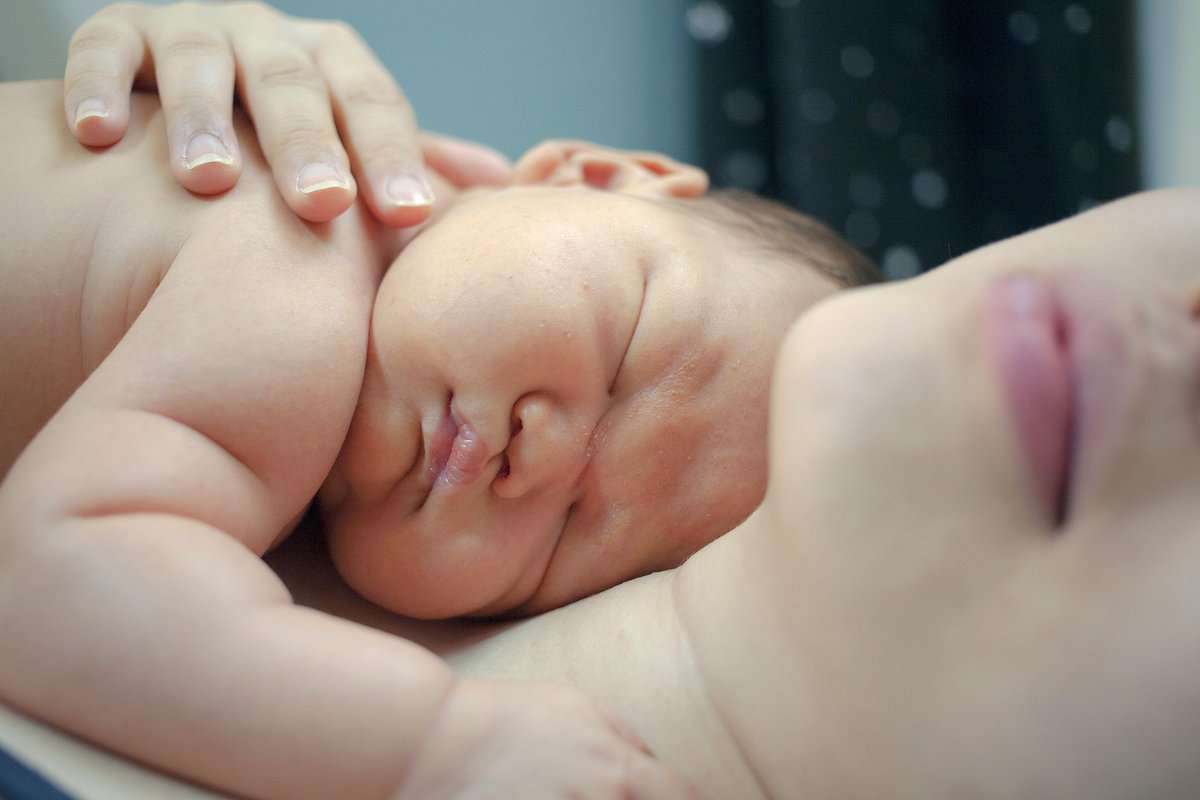 Ein Neugeborenes auf der Brust der Mutter. Bonding findet auch bei einem Kaiserschnitt statt.