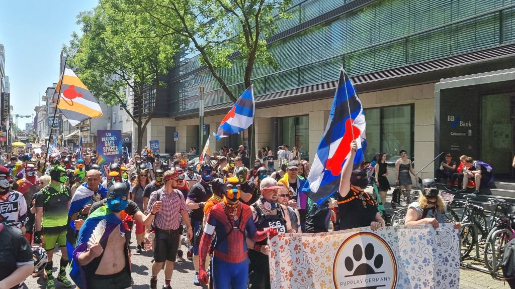 PupPlayer halten den PupPlay-Banner und Flaggen auf einem CSD hoch